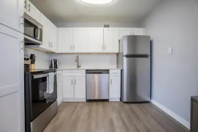 a kitchen with white cabinets and a stainless steel refrigerator at Landing Stunning Studio Game Room Pool in Fort Wayne