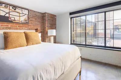 a bedroom with a large bed and a brick wall at Landing Amazing 2BD Gym Courtyard in Cleveland
