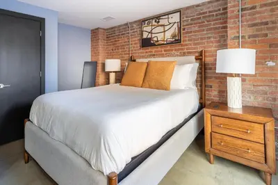 a bedroom with a large bed and a brick wall at Landing Amazing 2BD Gym Courtyard in Cleveland