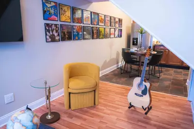 a living room with a chair and a guitar at Bright and Hip 2BR Condo in Heart of Ohio City in Cleveland