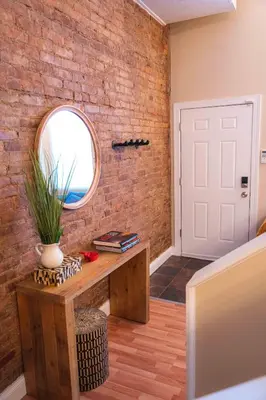 a room with a brick wall and a table and a window at Bright and Hip 2BR Condo in Heart of Ohio City in Cleveland