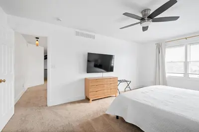 a white bedroom with a bed and a flat screen tv at Nookside Grand Estate For 8 in Hamilton