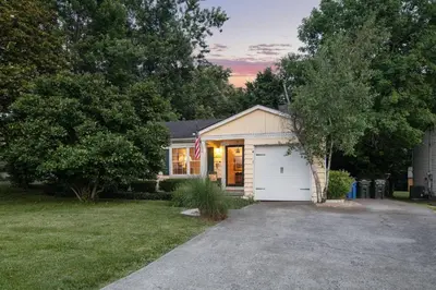 a house with a garage and an american flag at Charming Cottage | Near I-75 & Horse Park + Farms in Lexington