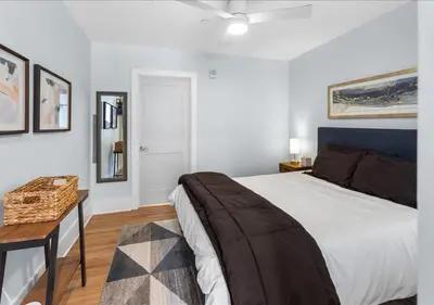 a white bedroom with a bed and a table and pictures at OTR - Court Street Entertainment District Cincinnati in Cincinnati