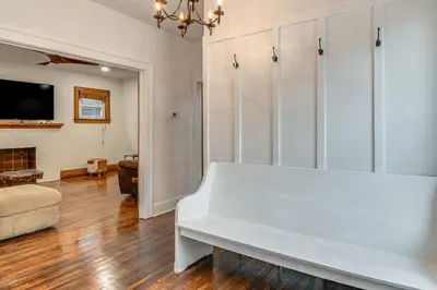 a white bench in a living room with a fireplace at Walk to Marshall University Home with Private Yard! in Huntington