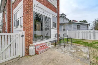 a house with a window and a chair on a patio at Walk to Marshall University Home with Private Yard! in Huntington