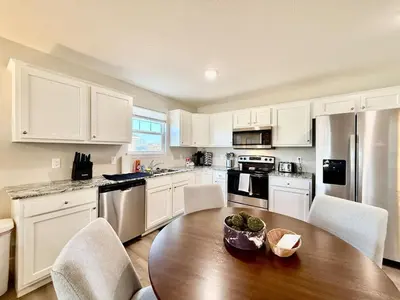 a kitchen with a wooden table and white cabinets at Cozy Equestrian Themed Getaway in Wilmington in Wilmington