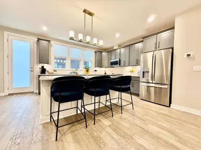 a kitchen with a counter and two bar stools at Stunning Executive Townhome Liberty Twp in Wetherington