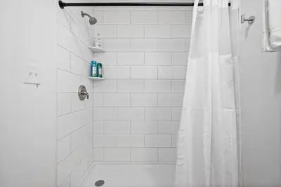 a white bathroom with a shower with a shower curtain at Rivers Edge Retreat For 10ppl in Dayton