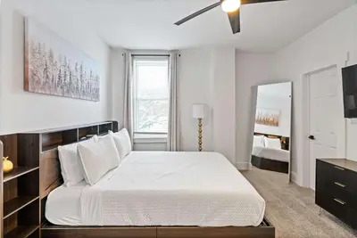 a white bedroom with a large bed and a mirror at Rivers Edge Retreat For 10ppl in Dayton
