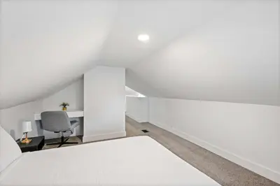 an attic bedroom with a white bed and a desk at Rivers Edge Retreat For 10ppl in Dayton