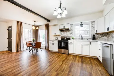a kitchen with white cabinets and a wooden floor at Serenity on Sanford in Portsmouth