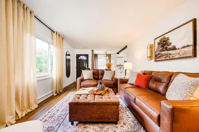 a living room with a brown leather couch and a table at Serenity on Sanford in Portsmouth