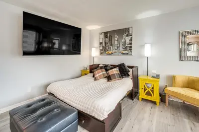 a bedroom with a bed and a yellow chair at 6 Mi to Downtown Cleveland Lakeview Condo! in Lakewood