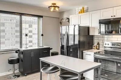 a kitchen with a white table and black appliances at 6 Mi to Downtown Cleveland Lakeview Condo! in Lakewood