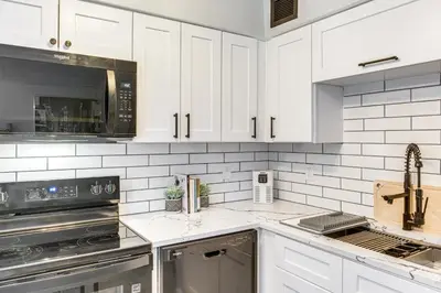 a kitchen with white cabinets and stainless steel appliances at 6 Mi to Downtown Cleveland Lakeview Condo! in Lakewood
