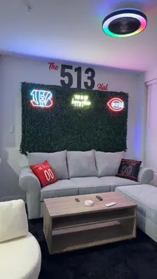 a living room with a couch and some neon signs at The 513 Flat 2! 1BR, 1Bath Apt with Pool and Riverfront View! Free Gated Parking! Only Steps from The banks & Stadiums! in Cincinnati