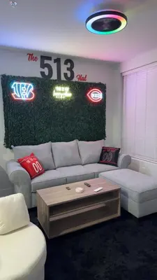 a living room with a couch and signs on the wall at The 513 Flat 2! 1BR, 1Bath Apt with Pool and Riverfront View! Free Gated Parking! Only Steps from The banks & Stadiums! in Cincinnati