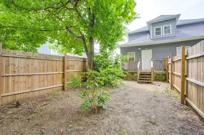 a wooden fence in front of a house with a tree at Quiet & Spacious Home Near Downtown in Columbus