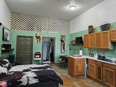 a bedroom with a bed and a desk and a kitchen at Secluded one room house on 235 acres in Salem