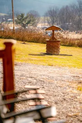 a park bench with a small umbrella in the grass at Cedar Wrapped Cozy Villa Cabin - 4 miles from Trails in Laurelville