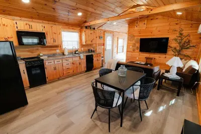 a kitchen and living room with a table and chairs at Cedar Wrapped Cozy Villa Cabin - 4 miles from Trails in Laurelville