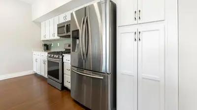 a stainless steel refrigerator in a kitchen with white cabinets at Landing Spectacular 2BD Gym in Cleveland