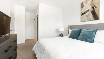 a white bedroom with a bed and a flat screen tv at Landing Spectacular 2BD Gym in Cleveland