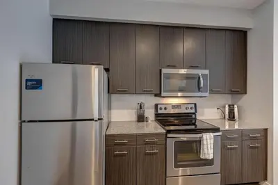 a kitchen with stainless steel appliances and wooden cabinets at Landing Stylish 1BD Yoga Studio Gym in Grove City