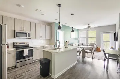 a kitchen with white cabinets and a dining room with a table at Landing Apartment - Tapestry Ridge in Fort Wright