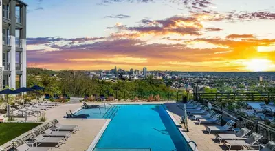 a swimming pool with lounge chairs and a city skyline at Landing Apartment - Tapestry Ridge in Fort Wright