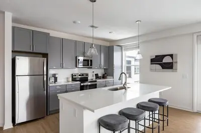 a kitchen with gray cabinets and a kitchen island with bar stools at Landing Stunning 2BD in Manhattan Harbour in Cincinnati