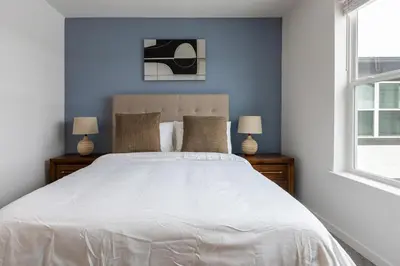 a bedroom with a large white bed with two lamps at Landing Stunning 2BD in Manhattan Harbour in Cincinnati