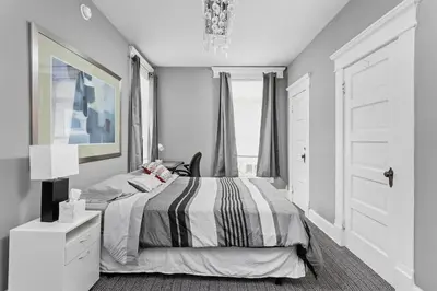 a white bedroom with a bed and a chandelier at Elegant 1BR Workspace Near Parks and Summit Lake in New Castle