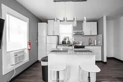 a kitchen with white appliances and a counter with stools at New Castle Getaway with Fireplace Garage & Near Attractions-Family Friendly in New Castle