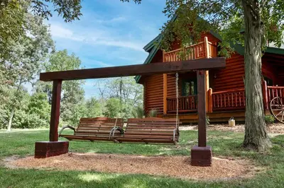 a park bench in front of a log cabin at Family-Favorite Cabin with Private Seasonal Pool and Movie Theater in Celina