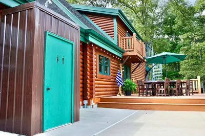 a log cabin with a green door and a patio at Family-Favorite Cabin with Private Seasonal Pool and Movie Theater in Celina