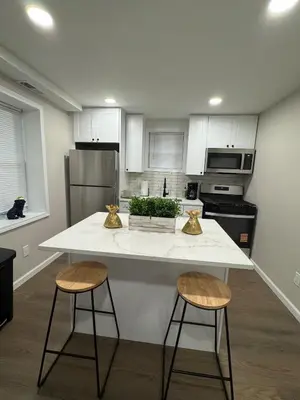 a kitchen with a white counter and two bar stools at Brand new first floor studio in quiet neighborhood in Akron