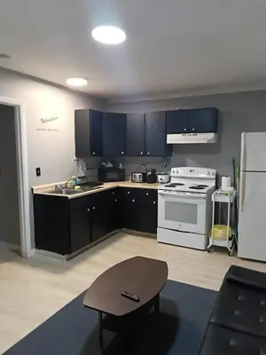 a kitchen with black cabinets and a white stove at Cosy single-level home with laundry and parking in Huntington