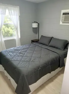 a large bed in a bedroom with a window at Cosy single-level home with laundry and parking in Huntington