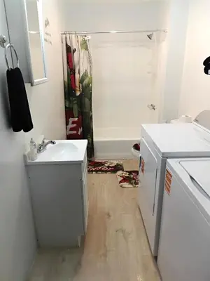 a white bathroom with a sink and a shower at Cosy single-level home with laundry and parking in Huntington