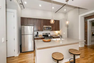 a kitchen with a stainless steel refrigerator and wooden cabinets at Gimme Shelter - OTR Cininnati in Cincinnati