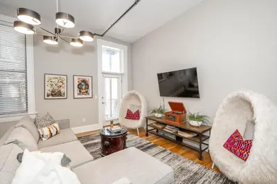 a living room with a couch and chairs and a tv at Gimme Shelter - OTR Cininnati in Cincinnati