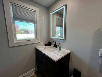 a bathroom with a sink and a mirror at 30 Something Quiet 3BR House Near I-77 & US-250 in New Philadelphia