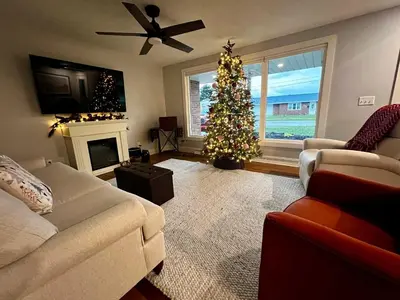 a living room with a christmas tree in front of a fireplace at 30 Something Quiet 3BR House Near I-77 & US-250 in New Philadelphia