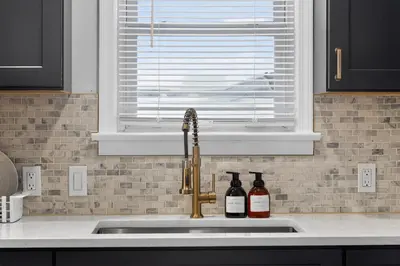 a kitchen sink with two bottles of wine next to a window at Stunning Home 15 Min to Downtown & Airport in Parma