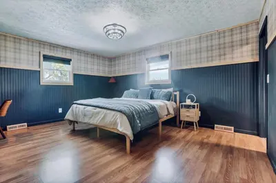 a bedroom with a bed with blue walls and wooden floors at The Nook on the Farm with Pool,Hot tub and Games in Pataskala