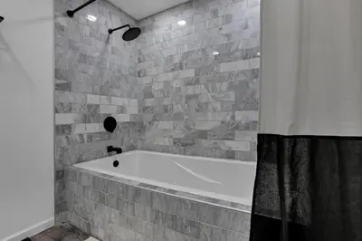 a bathroom with a white tub and a brick wall at The Nook on the Farm with Pool,Hot tub and Games in Pataskala