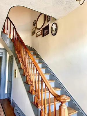 a staircase in a home with a clock on the wall at Historic King House Above The Keep Tavern