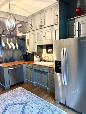 a kitchen with blue cabinets and a stainless steel refrigerator at Historic King House Above The Keep Tavern
